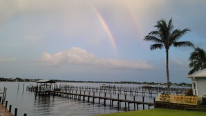 A waterfront property with a dock, a palm tree, and a view of the water. - Historic 4-bedroom/2 bath house on St Lucie River-Big Water Views (Stuart)