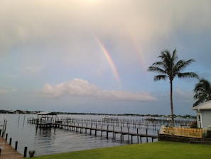 A waterfront property with a dock, a palm tree, and a view of the water. - Historic 4-bedroom/2 bath house on St Lucie River-Big Water Views (Stuart)