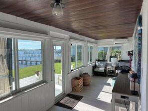 A covered porch with a view of a dock and water, wooden flooring, a chair, a table, and a small kitchenette area. - Historic waterfront 4-bedroom, 2 bath house on St Lucie River-Big Water Views (Stuart)