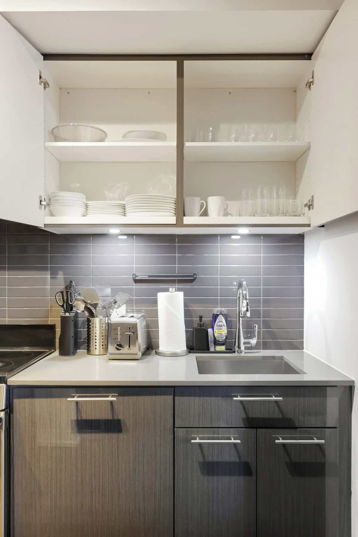 A modern kitchen with a built-in dishwasher, a sink, and a countertop with various kitchen utensils and appliances.