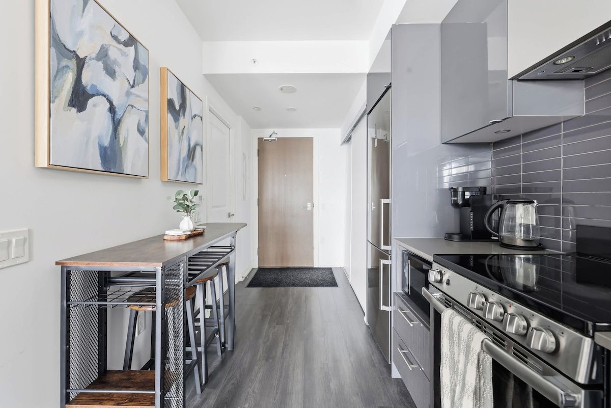 A modern kitchen with a central island, stainless steel appliances, and abstract wall art.