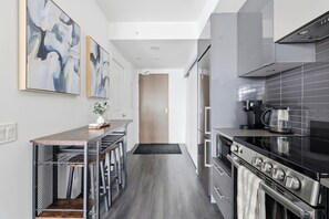 Una cocina moderna con una isla central, electrodomésticos de acero inoxidable y arte abstracto en la pared.