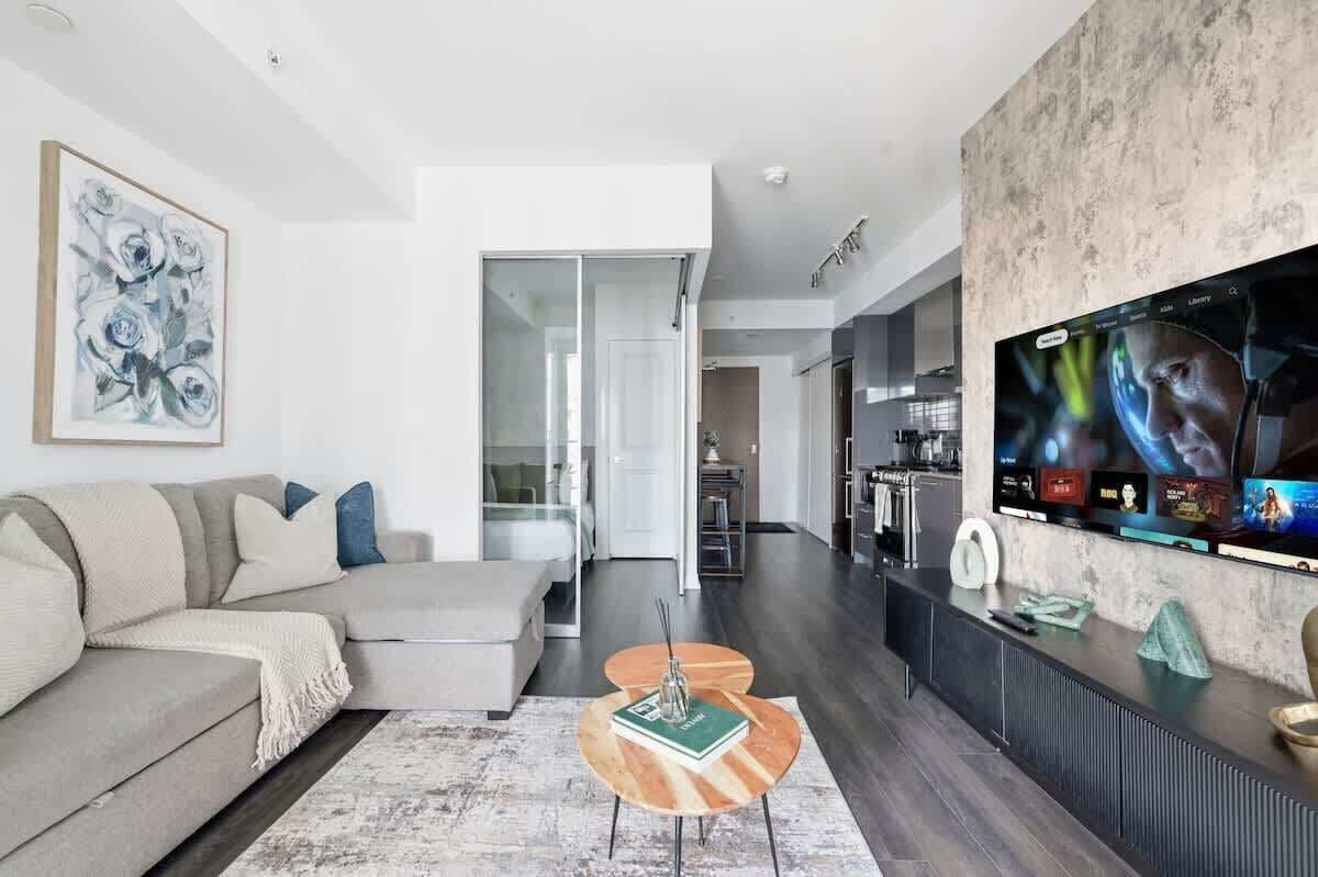A modern living room with a sofa, a coffee table, and a TV mounted on the wall.