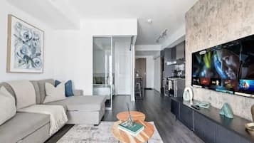 A modern living room with a sofa, a coffee table, and a TV mounted on the wall.