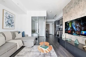 Una sala de estar moderna con un sofá, una mesa de centro y un televisor montado en la pared.
