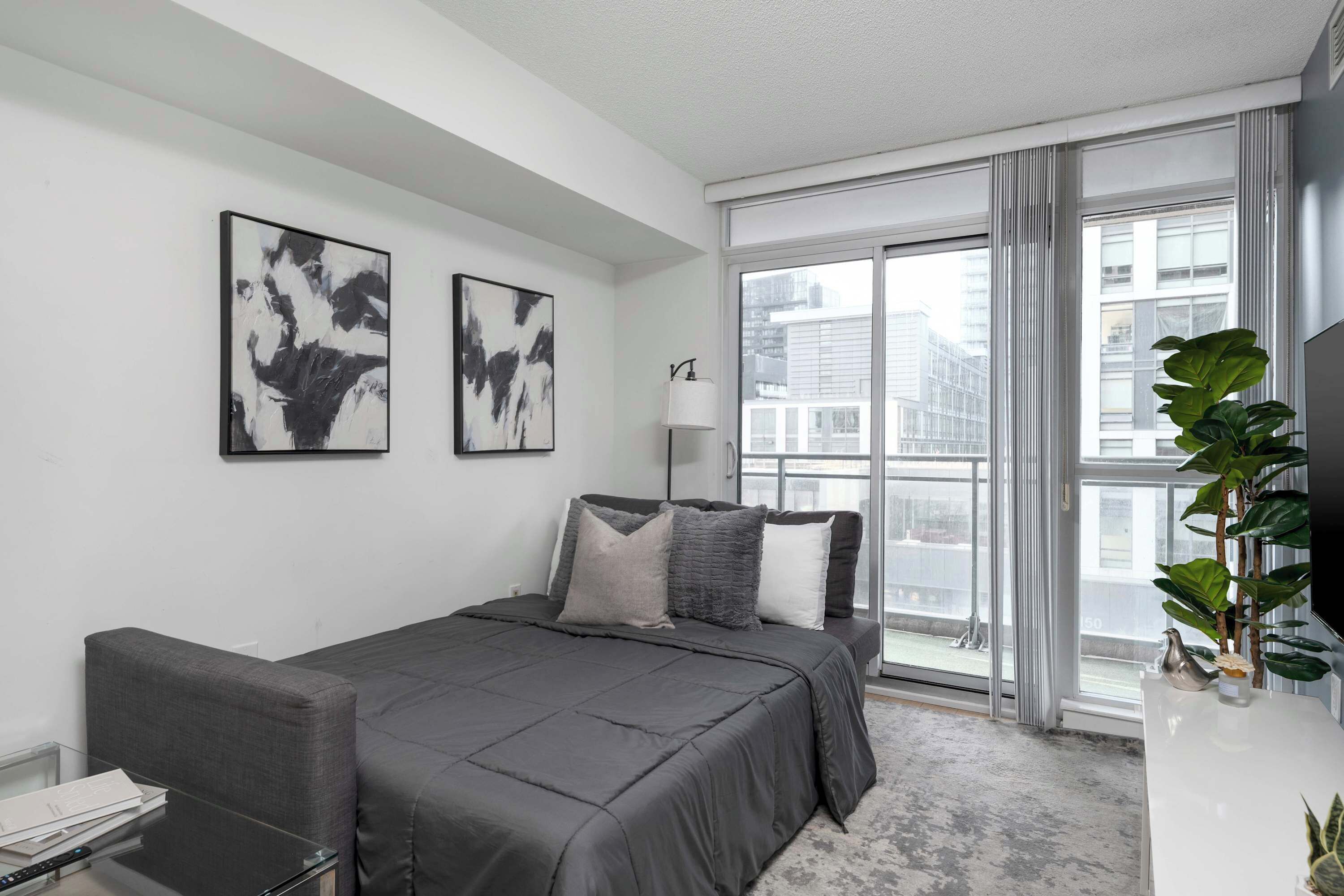 A modern bedroom with a bed, a desk, and a large window.