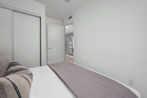 A bedroom with a bed, a bedside table, a wardrobe, and a mirror. - Walk to Rogers Centre, CN Tower, Waterfront!  | Parking Available (Toronto)