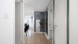 A hallway with a wooden floor, a white door on the left, and a large mirror on the right. - Walk to Rogers Centre, CN Tower, Waterfront! (Toronto)