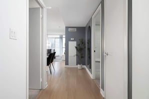 Ein Flur mit Holzboden, einer weißen Tür links und einem großen Spiegel rechts.
