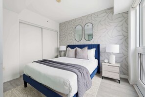 Une chambre moderne avec un grand lit, deux tables de chevet et un mur orné d’un motif.