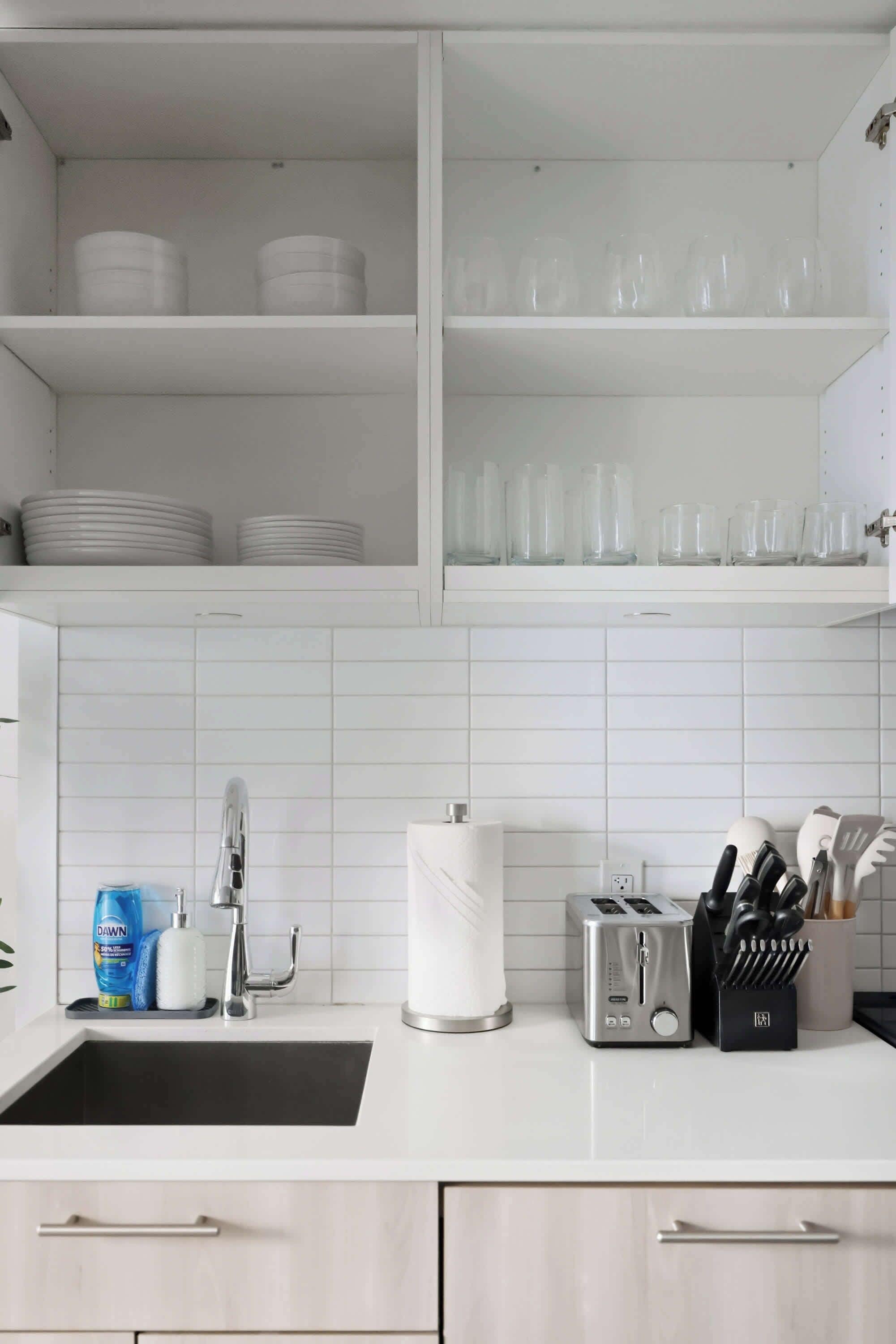 A kitchen with white cabinets, a sink, a toaster, and a utensil holder.