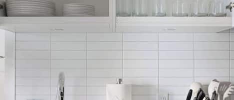 A kitchen with white cabinets, a sink, a toaster, and a utensil holder.