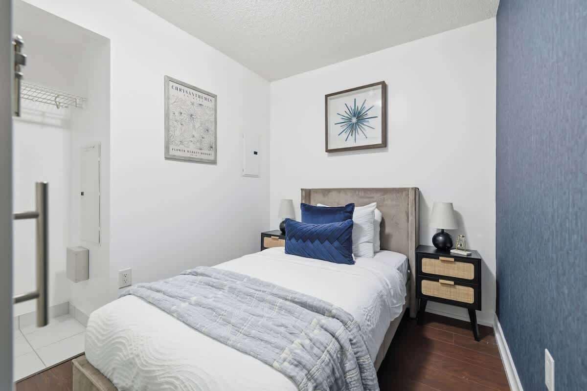 A bedroom with a bed, nightstands, a wall-mounted lamp, and a framed picture.