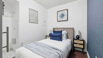 A bedroom with a bed, nightstands, a wall-mounted lamp, and a framed picture.