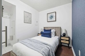 A bedroom with a bed, nightstands, a wall-mounted lamp, and a framed picture.