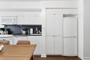 A modern kitchen with white cabinetry, a microwave, a stove, and a refrigerator. - Sleek 2BR Waterfront Condo Perfect City Getaway | Parking Available (Toronto)