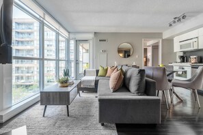 Ein modernes Wohnzimmer mit grauem Sofa, einem Couchtisch und einem Essbereich mit Stühlen.