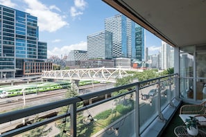 Un balcó amb vista a la ciutat, incloent una via de tren i edificis moderns.