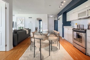 A modern kitchen with a built-in microwave, stove, and a small refrigerator. - Expansive 3BR Downtown Condo with Patio (Toronto)