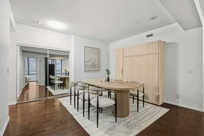 Un espace repas moderne avec une table ronde et des chaises, un tapis de couleur claire et une armoire en bois.