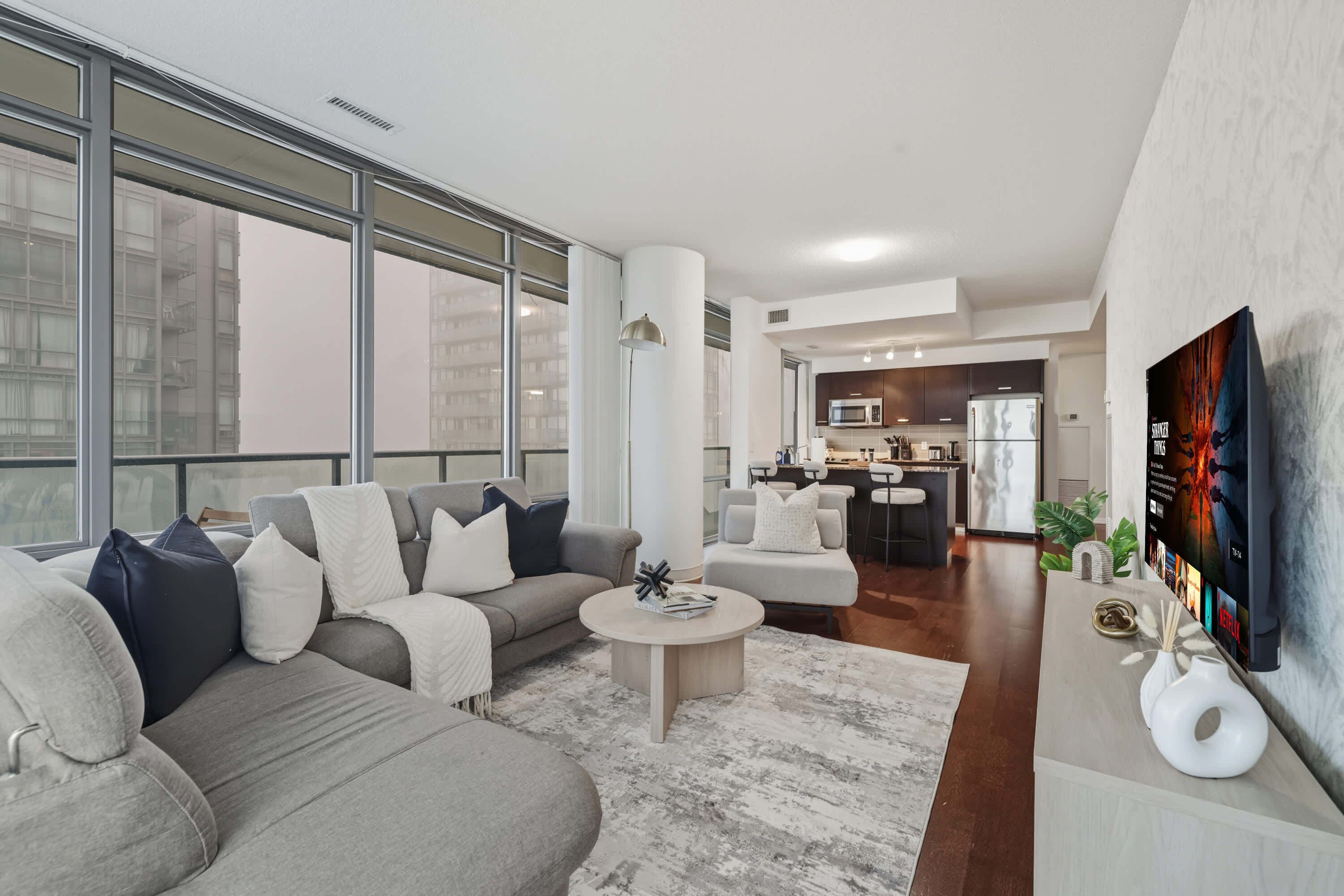 A modern living room with a large sofa, a coffee table, and a TV mounted on the wall.