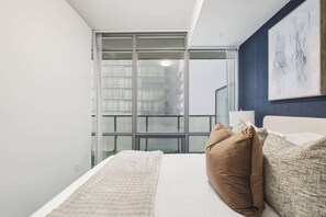 Une chambre d’hôtel avec une grande fenêtre, un lit avec des oreillers et un tableau au mur.