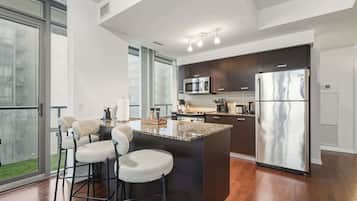 A modern kitchen with a large island, stainless steel appliances, and a view to the outside.