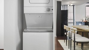 En lille, hvid vaskemaskine med kontrolpanel og et lille opbevaringsrum.