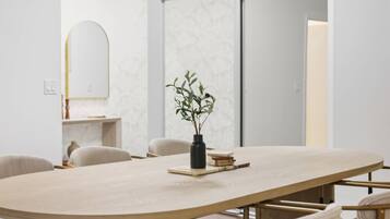 A modern dining area with a round table, chairs, and a vase with a plant.