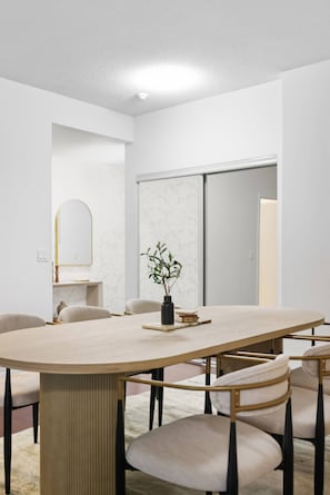 A modern dining area with a round table, chairs, and a vase with a plant.
