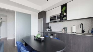 A modern kitchen with a central island, dark cabinetry, and a herringbone tile backsplash.