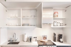 A modern kitchen with white cabinetry, a stainless steel sink, a built-in oven, and a coffee maker.