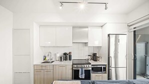 A modern kitchen with white cabinets, a stainless steel refrigerator, a stove, and a microwave. - City Living Downtown Retreat Perfect Getaway! (Toronto)