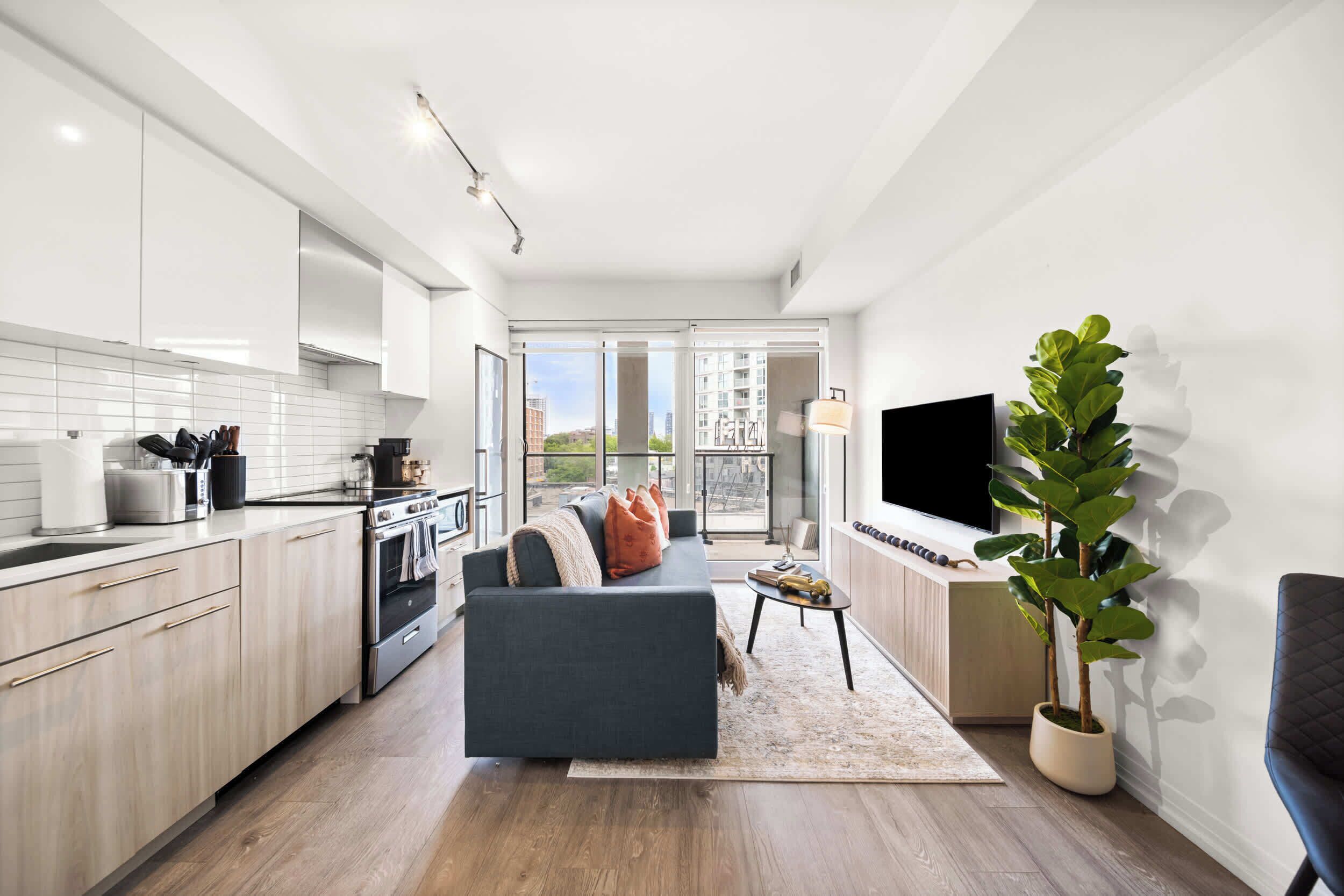 A modern kitchen with a dining area, a sofa, and a TV.
