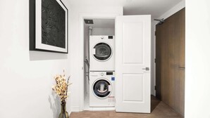 A laundry room with two stacked washing machines, a white door, and a framed artwork on the wall. - City Living Downtown Retreat Perfect Getaway! (Toronto)