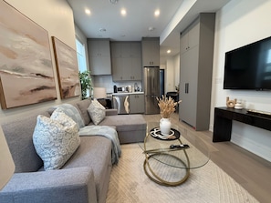 A modern living room with a grey sofa, a coffee table, and a flat-screen TV.