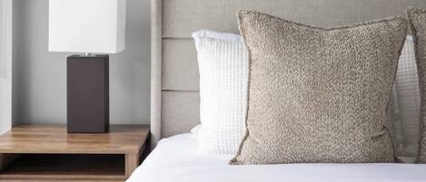 A bedroom with a bed, a nightstand, a lamp, and two framed pictures on the wall.