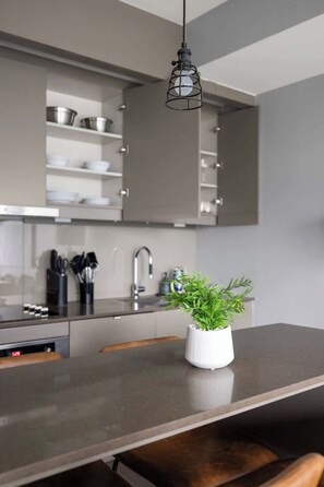 A modern kitchen with grey cabinets, a stainless steel sink, and a hanging light fixture. - Stunning 1BR Suite, Private Balcony & City Views | Parking Available (Toronto)
