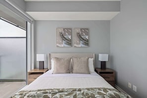 A bedroom with a large bed, two nightstands, a headboard, and two wall-mounted lamps. - Stunning 1BR Suite, Private Balcony & City Views | Parking Available (Toronto)