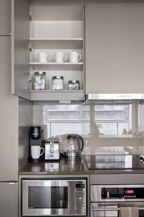 A modern kitchen with a built-in microwave, toaster, and coffee maker. - Stunning 1BR Suite, Private Balcony & City Views | Parking Available (Toronto)