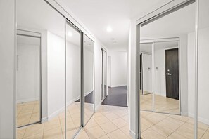Een gang met glazen deuren naar afzonderlijke kamers, betegelde vloer en een plafond met inbouwverlichting.