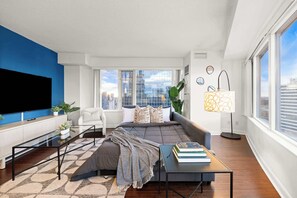 A modern living room with a sofa, coffee table, and a flat-screen TV. - Free Parking! Huge 3BR CityPlace Condo | Parking Available (Toronto)