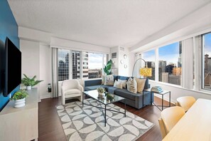 A modern living room with a sofa, armchairs, a coffee table, and a TV. - Free Parking! Huge 3BR CityPlace Condo | Parking Available (Toronto)