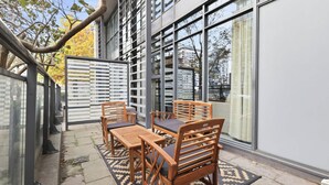 An outdoor seating area with a table and chairs, a patterned rug, and a glass partition. - Luxury DT Townhome Steps to Top Attractions! (Toronto)