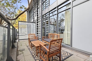 An outdoor seating area with a table and chairs, a patterned rug, and a glass partition. - Luxury DT Townhome Steps to Top Attractions! (Toronto)