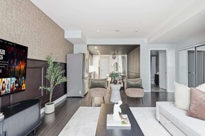 A modern living room with a flat-screen TV, a potted plant, a sofa, and a coffee table. - Luxury DT Townhome Steps to Top Attractions! (Toronto)