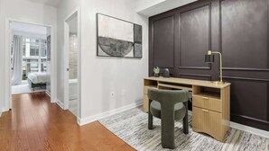 A modern home office with a desk, chair, and a large painting on the wall. - Luxury DT Townhome Steps to Top Attractions! (Toronto)
