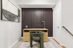 A hallway with a dark door, a desk with a lamp, a chair, and a patterned rug. - Luxury DT Townhome Steps to Top Attractions! (Toronto)