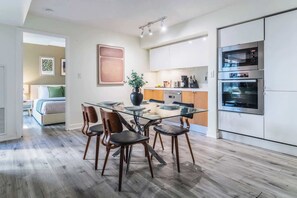 A modern kitchen with a glass dining table, wooden chairs, and stainless steel appliances. - Luxury Waterfront Escape Stylish 3BR Condo (Toronto)