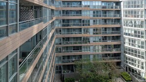 Een meerlaags gebouw met een modern architectonisch ontwerp, met grote glasgevels en een binnentuin met groen.